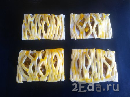 Верх сформированных слоек смазать взбитым желтком, выложить их на противень, застеленный антипригарным ковриком (или бумагой для выпечки). Выпекать в духовке, разогретой до 210 градусов, в течение 20 минут (до зарумянивания).