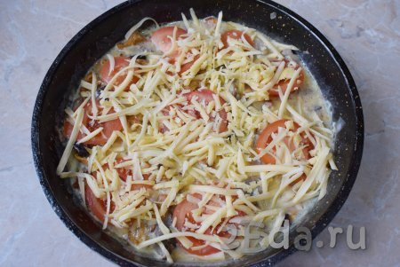 Верх омлета с грибами и помидорами посыпьте сыром, натёртым на тёрке. Накройте сковороду крышкой, сделайте маленький огонь и готовьте 5-6 минут.