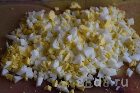 Для приготовления классического салата "Оливье" сначала надо сварить яйца вкрутую (яйца нужно полностью залить водой и варить 10 минут с момента закипания), затем охладить, очистить их от скорлупы и нарезать мелкими кубиками.