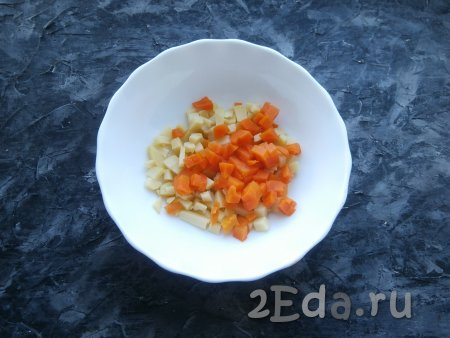 Картофель и морковь предварительно отварить в кожуре (варить 25-30 минут с начала кипения воды), остудить, очистить, а затем нарезать небольшими кубиками и выложить в миску.