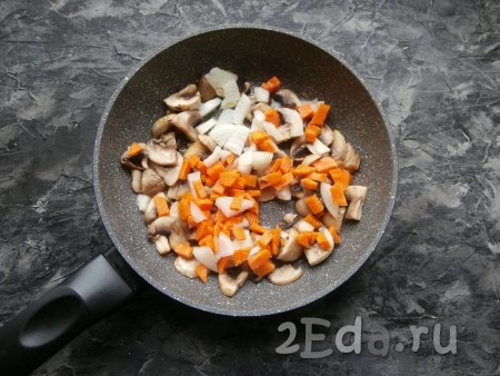 Обжарить грибы на среднем огне около 3-4 минут. Затем к шампиньонам добавить 1 некрупно нарезанную луковицу и нарезанную кубиками (или брусочками) морковку, перемешать. Обжаривать грибы с овощами, помешивая, минут 5.