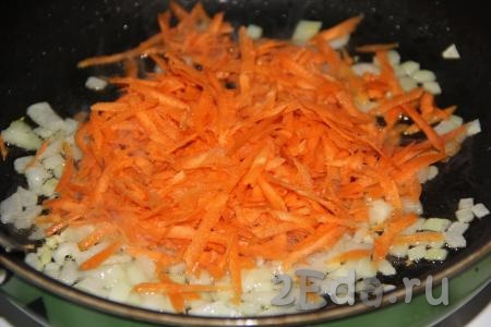 Очищенную морковь натереть на крупной тёрке, выложить в сковороду к луку и обжаривать 5 минут, помешивая.