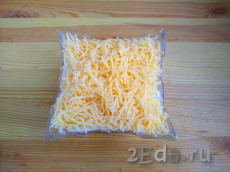 Поверх яичного слоя выложить сыр, натёртый на мелкой тёрке. Слой сыра должен лежать воздушной горкой, ничем смазывать его не нужно. Сыр должен напоминать пушистый снег.