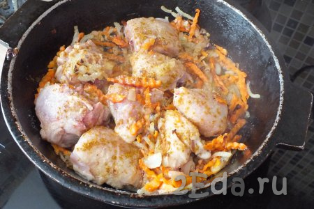 По истечении времени к луку с морковью выложите кусочки курицы, посолите, добавьте специи по вкусу. Обжаривайте курочку с двух сторон в течение 15 минут на среднем огне.