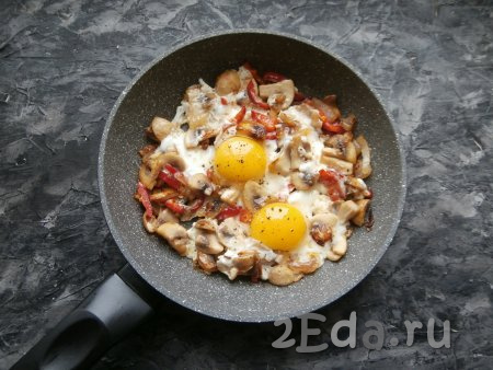 Вбить в сковороду яйца, посолить по вкусу и поперчить, прикрыть сковороду крышкой и на медленном огне выдержать яичницу с шампиньонами и луком 3-4 минуты. 