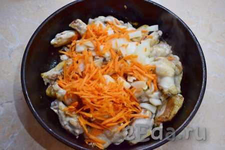В сковороду к обжаренным крылышкам добавьте измельчённые лук и морковь, перемешайте и обжарьте в течение 3-5 минут, пару раз перемешайте.