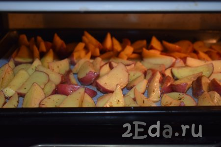 Отправляем противень с дольками картошки в разогретую духовку и запекаем минут 35-40 при температуре 190-200 градусов (продолжительность запекания регулируйте, ориентируясь на свою духовку, также на время приготовления влияет сорт картофеля).
