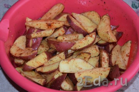 К картошке вливаем половину растительного масла, перемешиваем. Даём картофелю постоять и пропитаться солью, перцем и специями в течение 15-20 минут при комнатной температуре. За это время пару раз перемешиваем дольки картофеля.