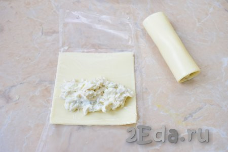 Пластинки плавленного сыра извлеките из упаковки и выложите на каждую пластину немного подготовленной начинки. Скрутите пластину в рулет.