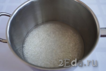 Начнём приготовление нежнейших тефтелек из индейки с отваривания риса. Для этого блюда рис нужно отварить до полуготовности (если добавить к фаршу сырой рис, он может остаться слишком плотным в готовом блюде). Поэтому берём 100 грамм риса (я предпочитаю «Краснодарский», но подойдёт и длиннозёрный) и тщательно промываем под проточной водой. Вода должна стать прозрачной. Далее перекладываем рис в сотейник и заливаем 200 мл воды. Ставим на огонь. После закипания рис варится буквально 5-7 минут.