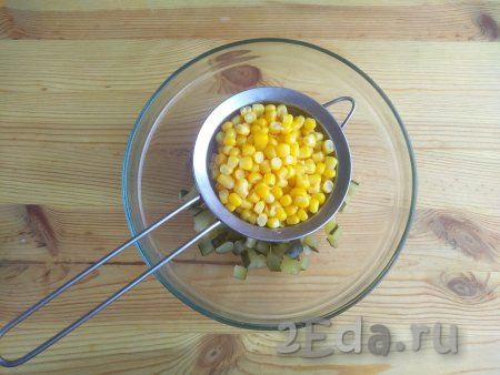 Консервированную кукурузу откинуть через сито, удалить излишки жидкости. Выложить зёрна кукурузы в миску к огурцам.