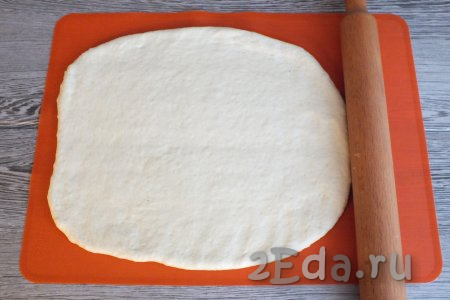 Через 30 минут тесто снова увеличится в объёме и будет готово к разделке. Раскатайте тесто на присыпанной мукой поверхности с помощью скалки в прямоугольной пласт толщиной 0,3 см. Важно, чтобы середина и края пласта были одинаковой толщины.
