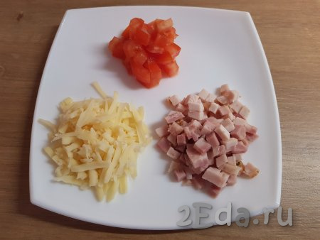 Натереть на крупной тёрке сыр,  нарезать на небольшие кубики помидор и ветчину (или варёную колбасу).