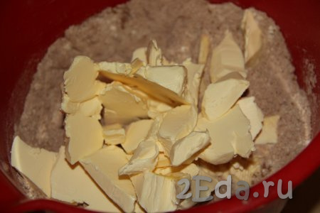 В смесь сухих ингредиентов добавить холодное масло (или маргарин), нарезанное на небольшие кусочки.