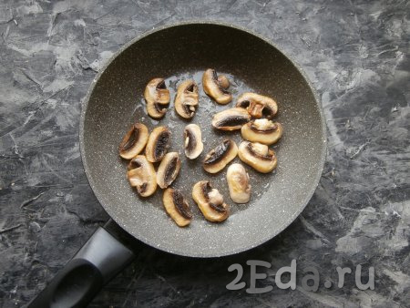 Выкладывать нарезанные шампиньоны на сковороду в один слой и обжаривать на небольшом количестве растительного масла на среднем огне до румяности с двух сторон. Жареные грибы переложить на тарелку и остудить.