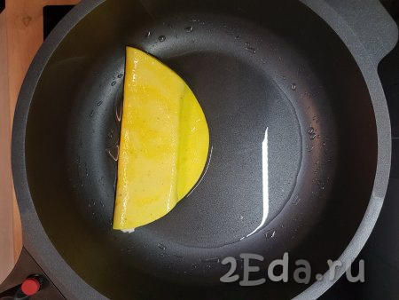 Желтки с сыром свернуть в рулет. Получившийся рулет подвинуть к бортику сковороды.