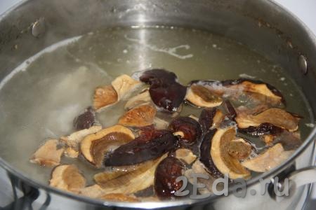 Добавить сушеные грибы и нарезанное куриное мясо в кипящий бульон. Варить грибы 25 минут на небольшом огне.