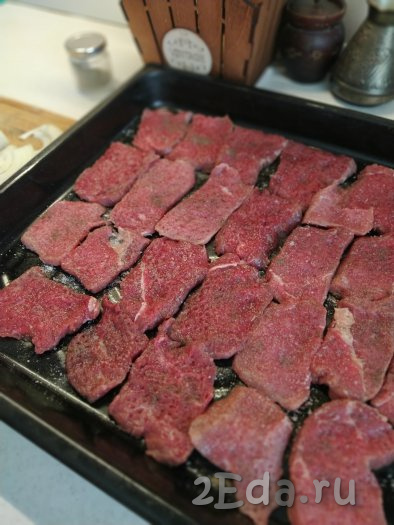 Выкладываем мясо на противень в один слой, солим и перчим по вкусу.