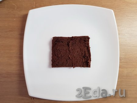Далее приступим к сборке пирожного, для этого на плоскую тарелку нужно выложить один кусочек коржа (края можно аккуратно подрезать у каждого из кусочков).