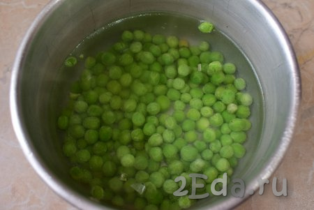 Если зелёный горошек свежий, то его можно сразу добавлять в блюдо. Если замороженный - необходимо, не размораживая его, выложить в кипящую воду, дать закипеть, а затем проварить 4-5 минут и слить лишнюю воду.
