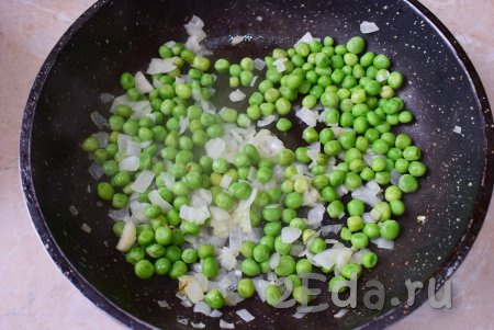 Добавьте в сковороду свежий (или предварительно отваренный) зелёный горошек, перемешайте его с луком и прогрейте в течение минуты, помешивая.