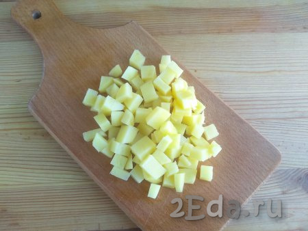 Картофель промыть в проточной воде, очистить от кожуры. Нарезать картошку кубиками с размером стороны, примерно, 1 см, промыть повторно. Переложить картофель в кастрюлю, залить 1,5 литрами воды, после закипания варить 5 минут на умеренном огне.
