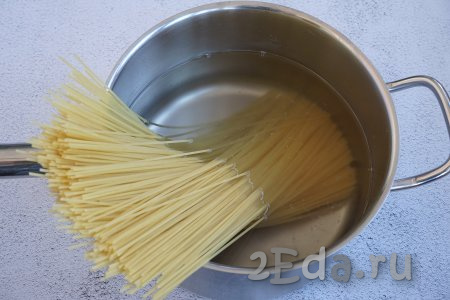 Вначале отварим спагетти, для этого наливаем в кастрюлю 2,5 литра воды, засыпаем 0,5 столовые ложки соли и отправляем на огонь. Помните, любые макаронные изделия кладутся только в кипящую воду. Дожидаемся, пока вода закипит, и закладываем спагетти. Когда макаронные изделия опустятся в кастрюлю, не забываем периодически помешивать, чтобы они не слиплись. Даём воде снова закипеть, уменьшаем огонь и варим спагетти 7-9 минут (точное время варки всегда указано на упаковке). В Италии спагетти всегда варят al dente, то есть оставляют слегка недоваренными, чтобы серединка была ещё белой. Я же предпочитаю варить до готовности в соответствии с инструкцией на упаковке.