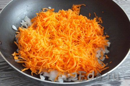 Когда лук станет мягким, выложите к нему очищенную и натёртую на средней тёрке морковь, хорошо перемешайте и обжаривайте, помешивая, в течение 5 минут.