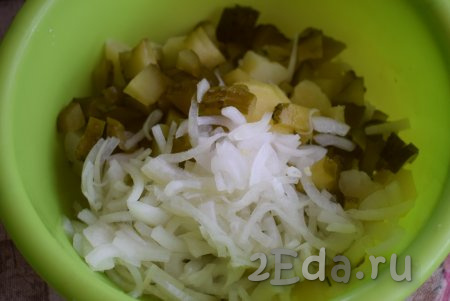 В глубокую миску выложить нарезанные картофель и огурцы. С лука слить всю жидкость и выложить его в миску.