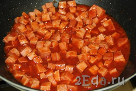 Перемешать колбасу с томатным соусом, дать закипеть, а затем потомить на небольшом огне пару минут.