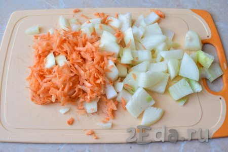 Пока кусочки курицы обжариваются, очистите луковицу и морковь. Лук нарежьте, а морковь натрите на крупной тёрке.