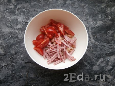 К фасоли добавить нарезанную соломкой (или тонкими брусочками) копчёную колбасу и нарезанные дольками помидоры.