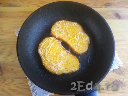 Сковороду с растительным маслом разогреть, выложить хлебные ломтики. Жарить гренки с сыром и яйцами на среднем огне около минуты (до зарумянивания). За это время яйцо «схватится», а сыр расплавится.