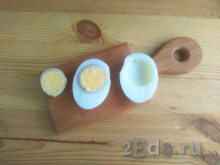 Яйца выложить в кастрюльку с холодной водой, поставить на огонь, а после закипания варить минут 8-10, затем воду слить. Варёные яйца залить холодной водой и оставить до полного остывания. Остывшие очищенные яйца разрезать пополам, разделить на желтки и белки. Половину одного желтка оставить для украшения.