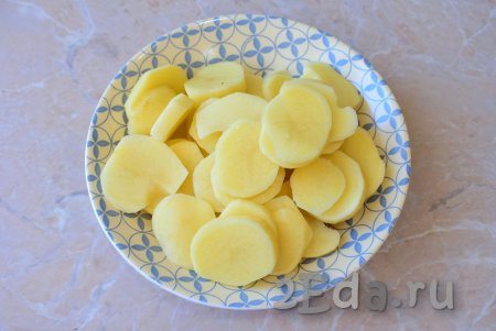 Очищенные картошины ополосните водой и нарежьте на кружочки средней толщины (совсем тонко нарезать картошку не нужно, но и толстыми ломтики картошки не должны быть).