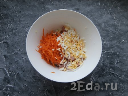 Свежую морковку и варёные яйца натереть на крупной тёрке, а затем выложить в салат из свежей капусты и колбасы.