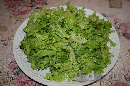 Листья салата вымыть и обсушить от воды. Порвать салатные листья на средние кусочки и выложить на блюдо, в котором будет подаваться салат.