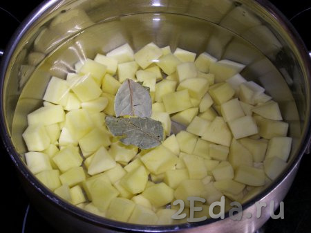 Перекладываем картофель в кастрюлю, в которой будут вариться щи, заливаем 2 литрами свежей холодной воды, добавляем соль и лавровые листья. По желанию, можно положить в воду с картофелем стебли укропа, очищенный корень петрушки, а также горошинки чёрного и душистого перцев. На сильном огне доводим воду до кипения, затем огонь уменьшаем и варим картофель минут 15-20 (до мягкости).