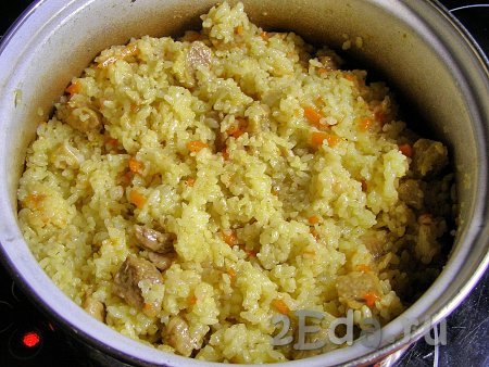 Аккуратно, снизу вверх перемешиваем плов так, чтобы мясо, лук и морковь равномерно распределились по рису.