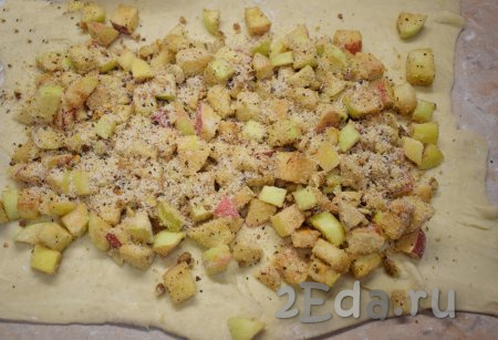 Выложите на тесто подготовленную начинку из яблок и орехов. Равномерно распределите её по всей поверхности, немного не доходя до краёв.