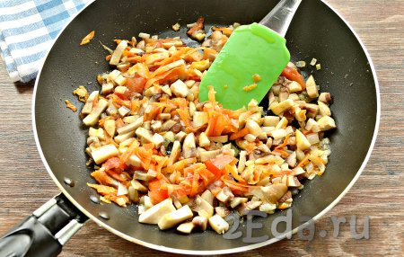 Нарезанные шампиньоны выложить в сковороду к овощам, перемешать. Тушить шампиньоны вместе с морковкой, луком и помидором 10 минут на малом огне, иногда помешивая.