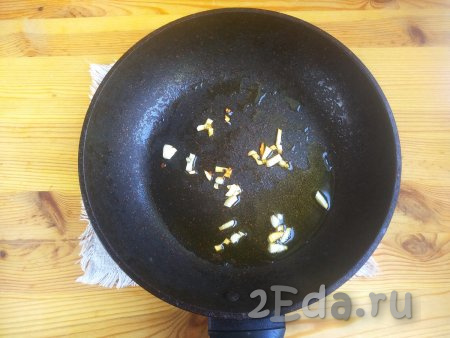 На сковороду вылить оливковое (или подсолнечное) масло, выложить чеснок. Обжарить кусочки чеснока на среднем огне в течение 30 секунд, чтобы появился характерный запах чеснока.