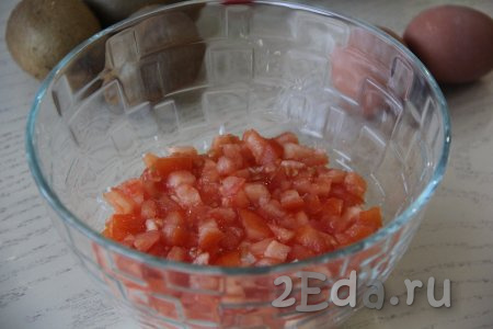 Вымыть 2 помидора, нарезать на мелкие кубики. Половину нарезанных помидоров выложить следующим слоем в салатник.