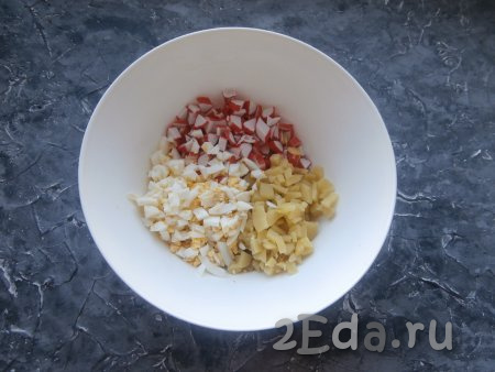 Нарезать остывшие картофель и яйца на небольшие кубики и выложить в салат из мяса курицы и крабовых палочек.