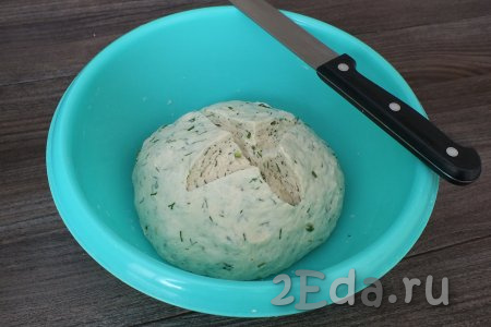 Обомните тесто, выложите в миску, снова сделайте крестообразный разрез. Накройте пищевой плёнкой и опять уберите в тёплое место на 50 минут.