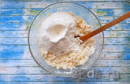 В творожно-кокосовую массу просеять муку, всыпать ванильный сахар и разрыхлитель, вначале замешивать тесто лопаточкой (или ложкой)