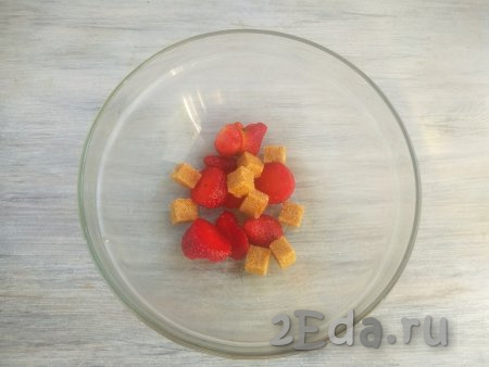 Вымыть свежую клубнику, очистить от чашелистиков. Если готовите с замороженными ягодами, разморозьте их, лишнюю жидкость слейте.  Разрезать ягоды на части и выложить в миску, добавить сахар.
