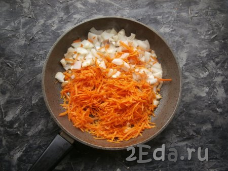 Почистить морковку и лук. 2 столовые ложки растительного масла влить в сковороду, в которой обжаривался хек, сюда же выложить морковку, натёртую на крупной тёрке, добавить нарезанный произвольными кусочками репчатый лук.