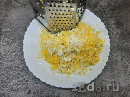 Яйца нужно сварить заранее (варим минут 8-9 с момента закипания воды, затем даём им полностью остыть и очищаем от скорлупы). Варёные яйца натереть в отдельную тарелку на мелкой тёрке.