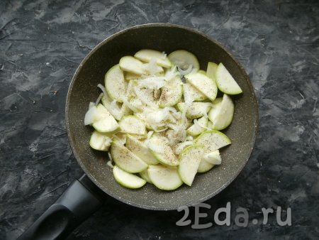Выложить кабачки в разогретую с растительным маслом сковороду, добавить нарезанный тонкими полукольцами очищенный репчатый лук. Овощи посолить и поперчить.